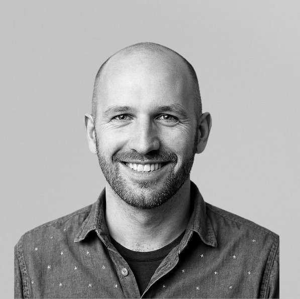 Portrait of a woman with brown hair on a flat gray background.